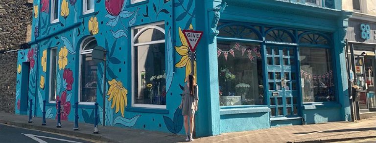 The corner of the building along the pavement, shopfront and mural together