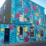 The side elevation of the building in turquoise, with the olive green rendered return alongside it