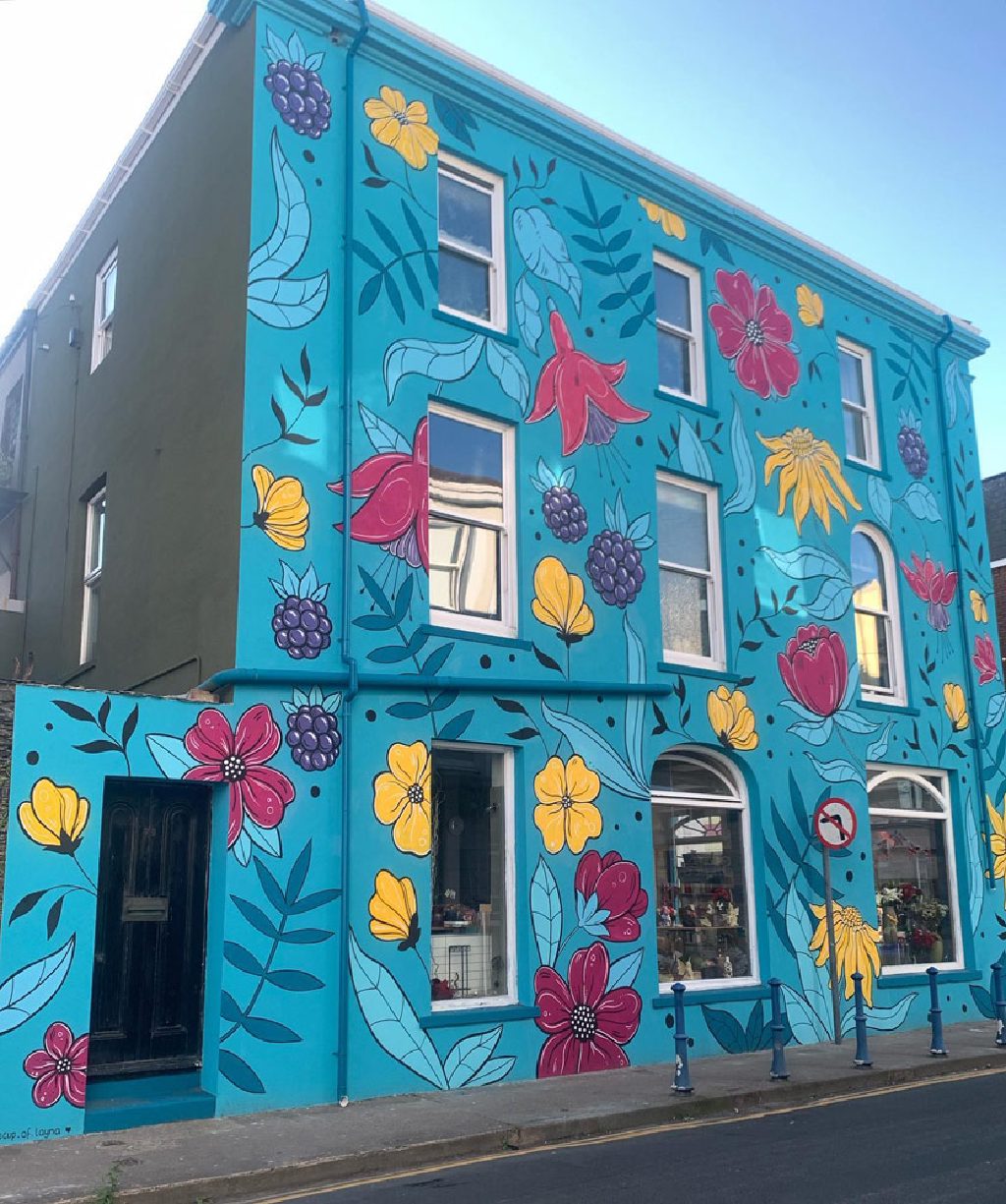 The side elevation of the building in turquoise, with the olive green rendered return alongside it
