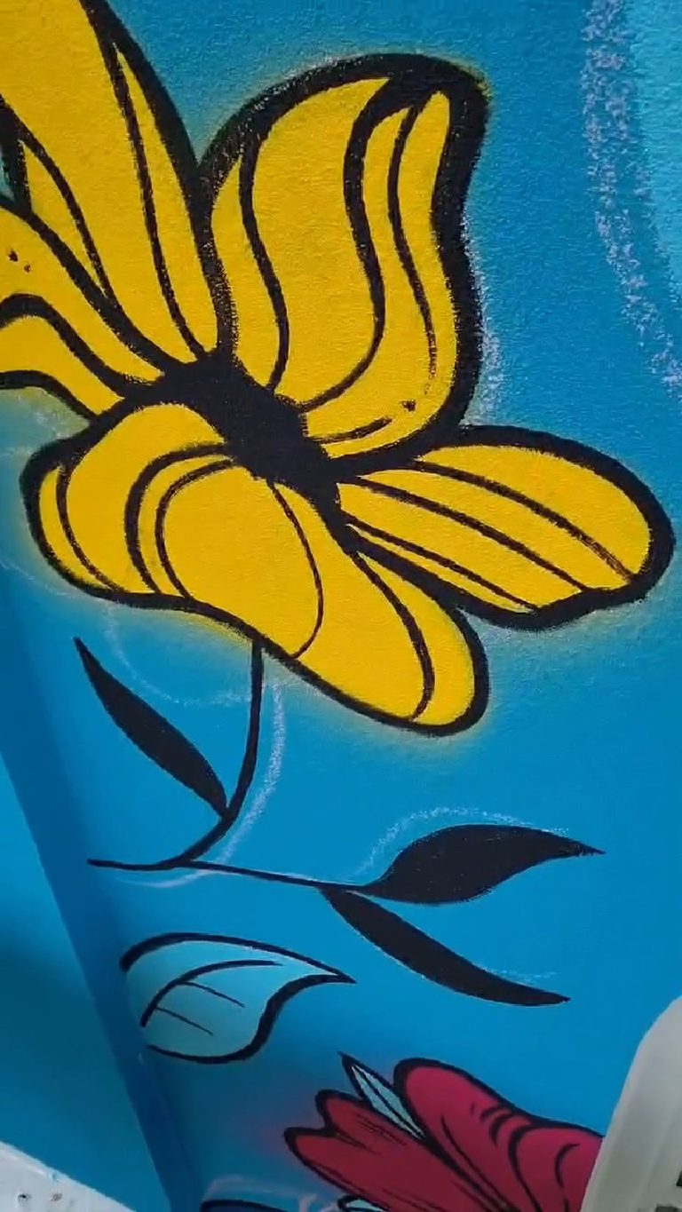 A finished yellow flower on the wall with the render texture showing through the paint