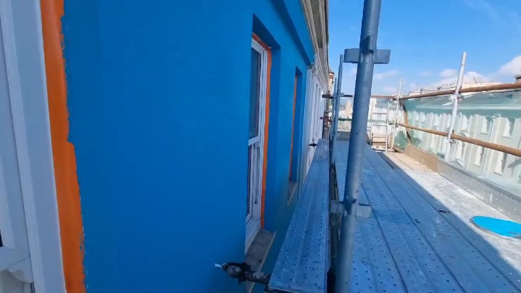The turquoise Light Weight Render System on the upper storey before any painting, seen along the scaffold