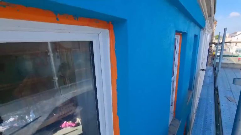 Close view of the render cut in around a window, the reveal masked off in orange tape