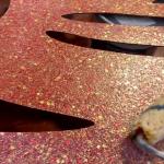 The Ilumitextra flake up close, red and gold specks across a rose ground