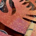 A roller working across the glittered surface between the cut feather slots