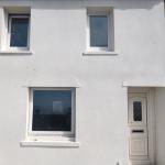 The finished front of the house in white ThermoCork render, windows, cills and door surround all cut in