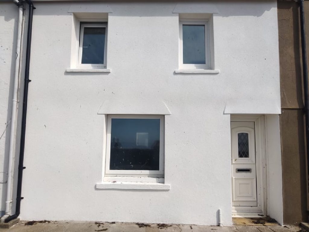 The finished front of the house in white ThermoCork render, windows, cills and door surround all cut in