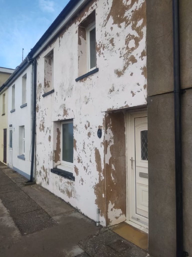 The front of the house before the work, seen along the terrace, the render peeling around the door and windows