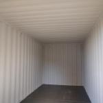 The full length of a container interior sprayed white over the corrugated steel walls and ceiling