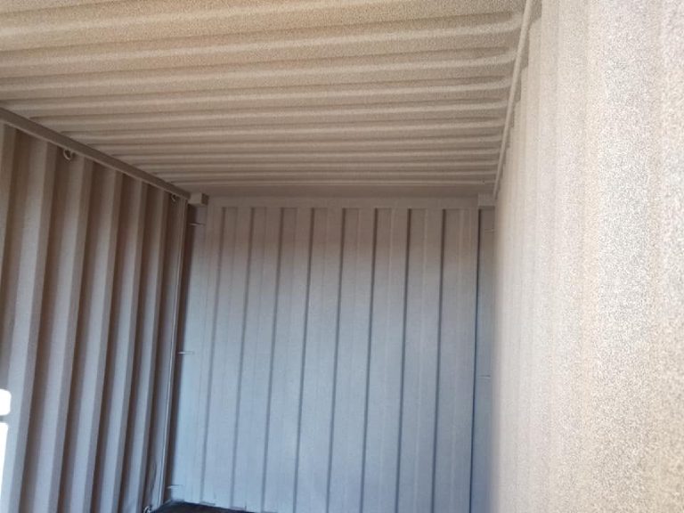 The container roof sprayed cream while the side and end walls are still bare grey steel