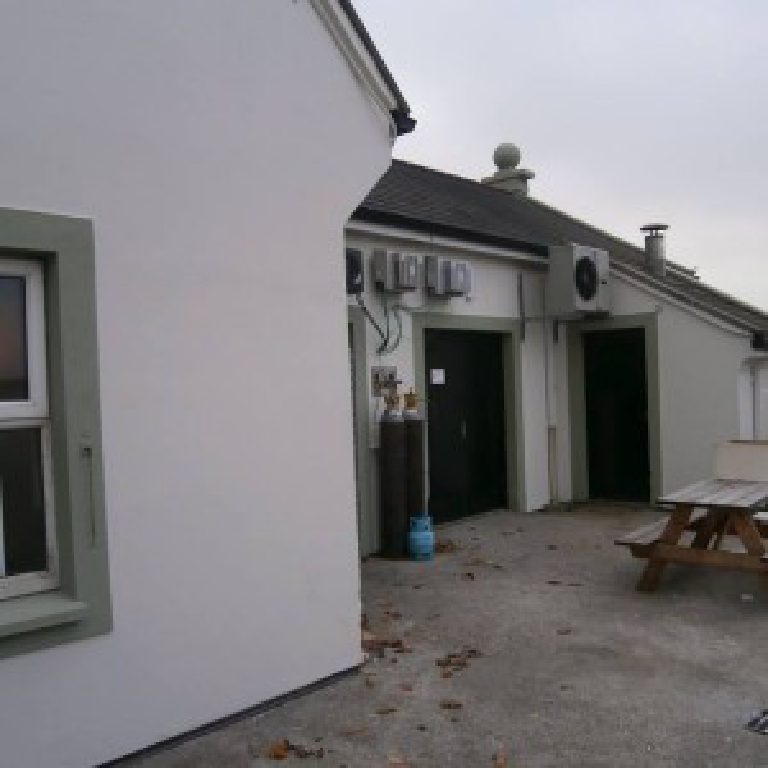 The service end of the yard, rendered walls, green painted door frames and gas bottles