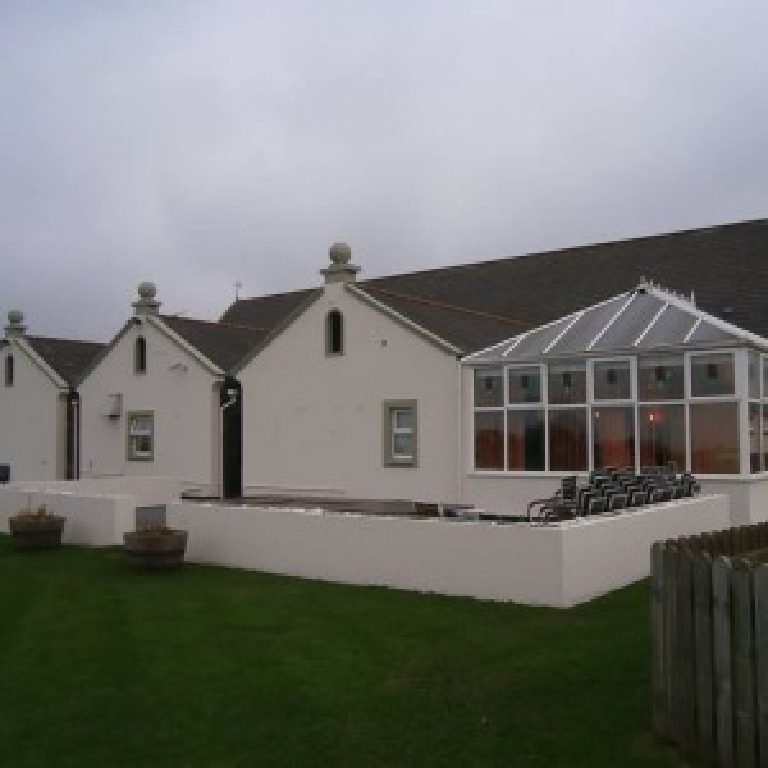 The back of the pub seen from the lawn, gabled bays with ball finials and the conservatory alongside