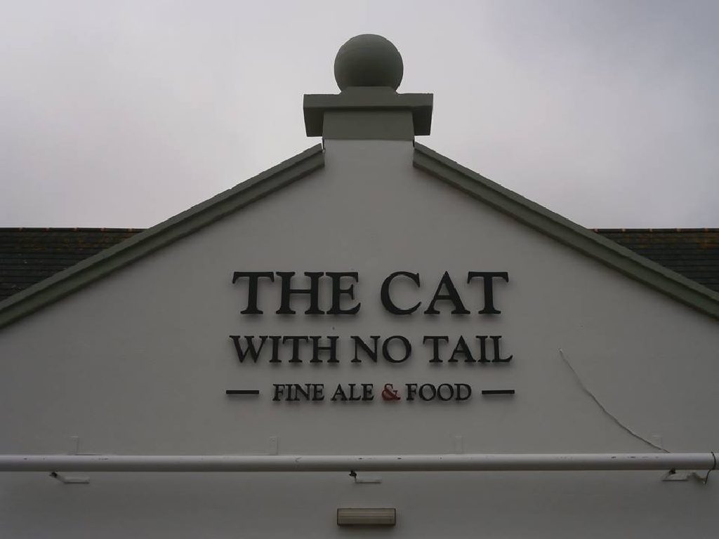 The pub name in raised lettering across the finished gable, ball finial above