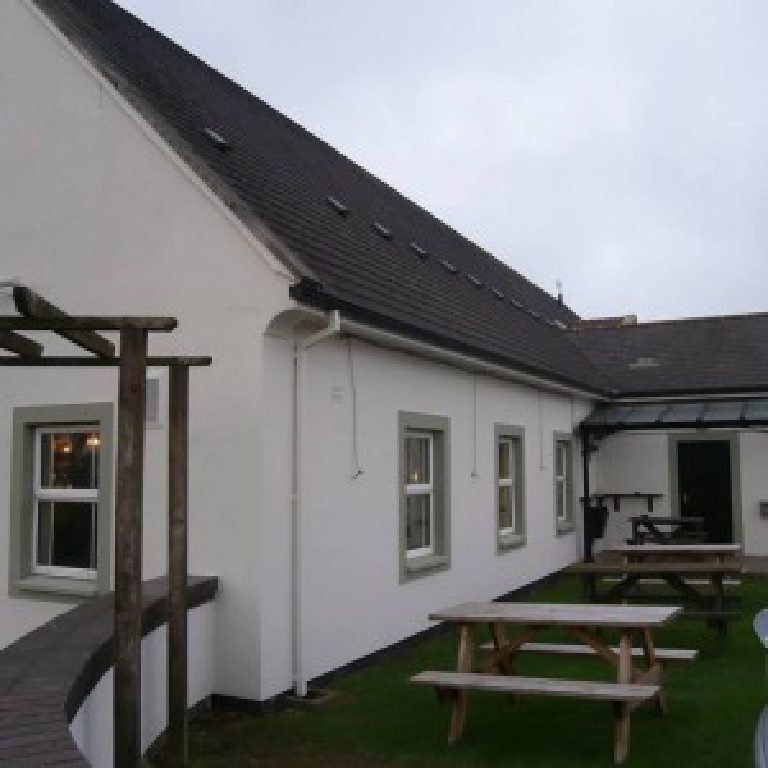 The long side elevation with sash windows and picnic tables out in the yard