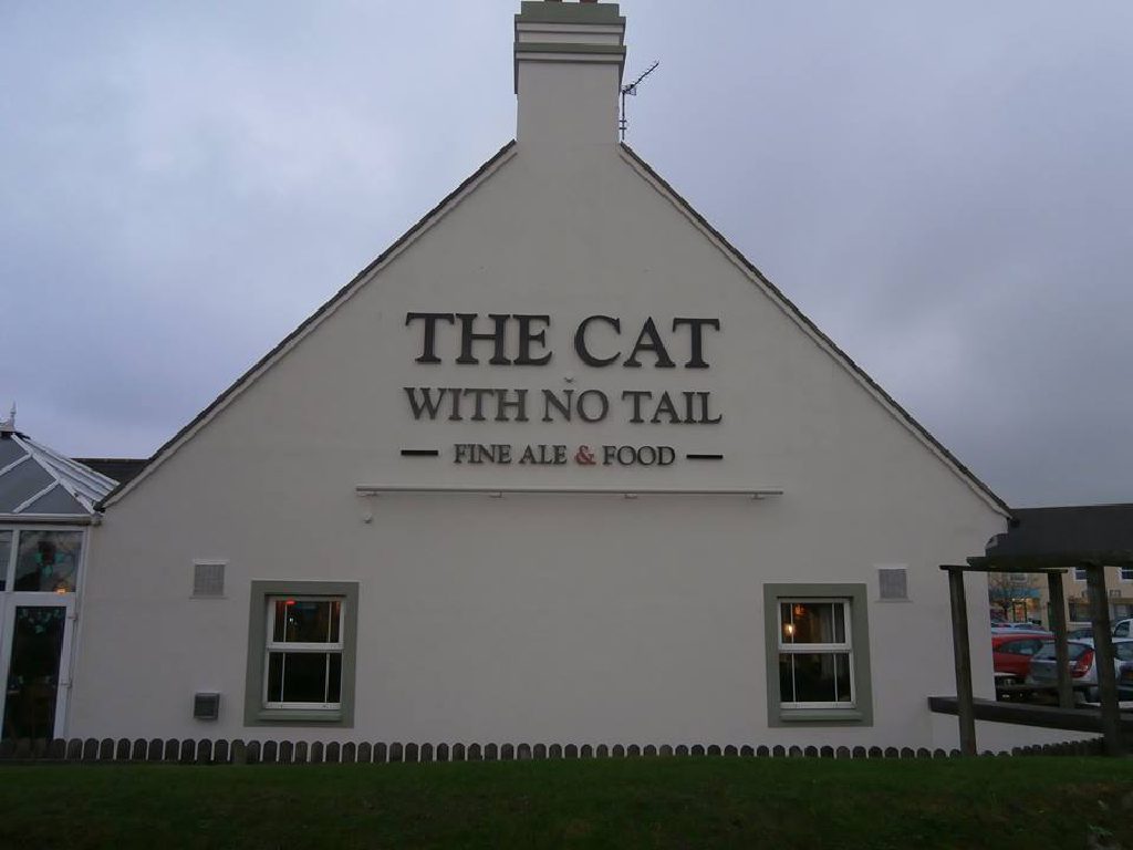The rendered gable of The Cat With No Tail with the pub signage across it