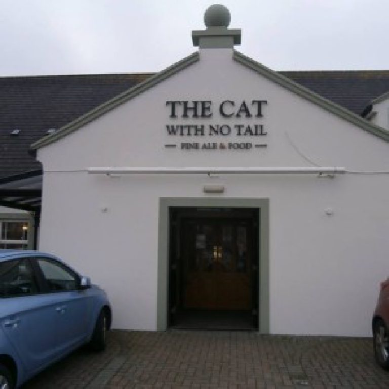 The entrance gable with the pub name over the doorway and a car parked in front