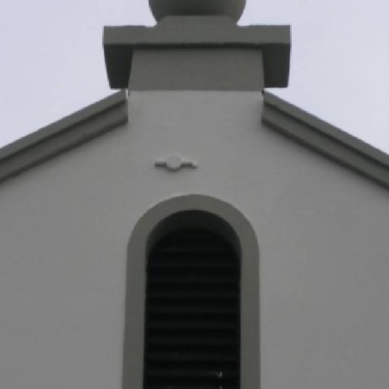 The apex of a gable, ball finial above an arched louvred vent