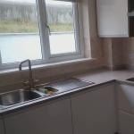 The kitchen with white and copper glitter walls and the orange splashback