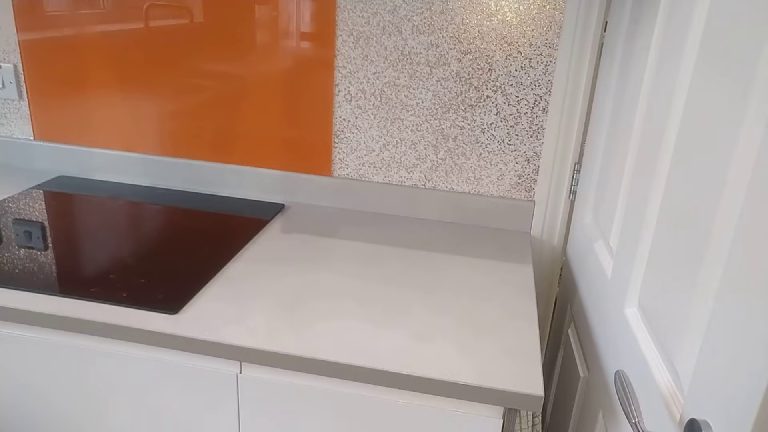 The finish running up to the orange glass splashback beside the hob